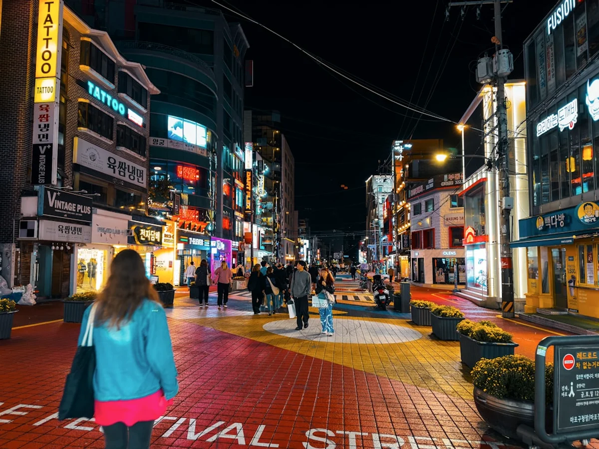 a group of people walking down a street at night